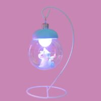 Sur un fond rose on voit une lampe lanterne transparente blanche avec une licorne bleue