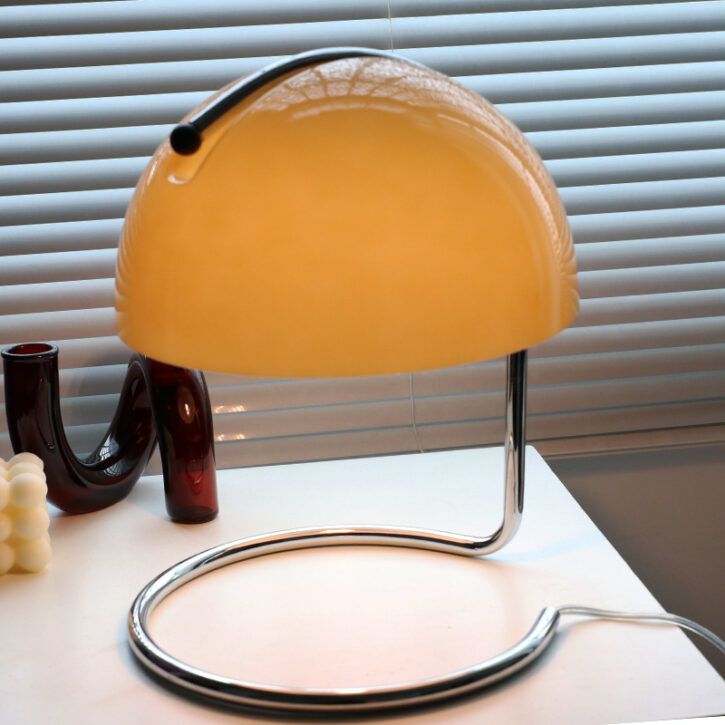 Une lampe de bureau avec un abat-jour arrondi orange en verre
