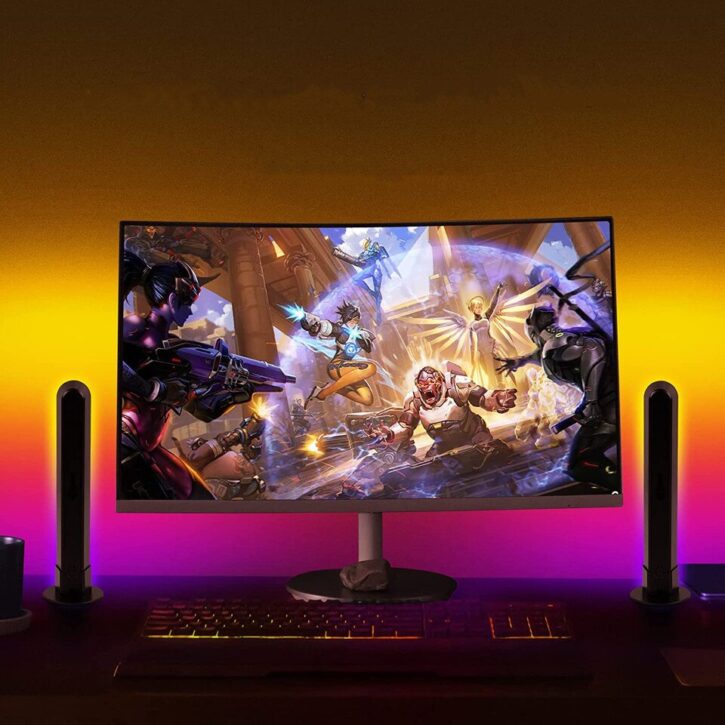 On peut voir un écran de gaming allumé sur un jeux vidéo, et sur ses deux côtés deux barres lumineuses qui éclairent en jaune et rose.